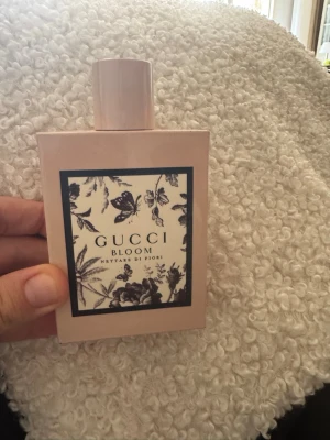Gucci Bloom  parfym - Gucci Bloom är en elegant parfym i en ljusrosa, rektangulär flaska med svartvit blommig etikett. Flaskan har en stilren, matt finish och ett matchande lock. Doften är blommig och exklusiv, perfekt för dig som vill ha något unikt och lyxigt. 100ml har sprutat några få gånger med doften var inte i min smak