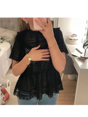Svart spetsblus med korta ärmar - Säljer en svart spetsblus med korta ärmar och hög hals. Blusen har ett vackert spetsmönster och volangdetaljer vid nederkanten. Perfekt att styla med jeans eller kjol för en trendig look.