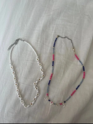 Färgglada pärlhalsband - Säljer flera halsband med pärlor i olika färger. Ett halsband har vita pärlor med blommor, ett har färgglada pärlor och bokstäver som bildar ordet 'LOVE'. De andra halsbanden är i blått, rosa och turkost. Perfekt för dig som gillar att mixa och matcha accessoarer. 