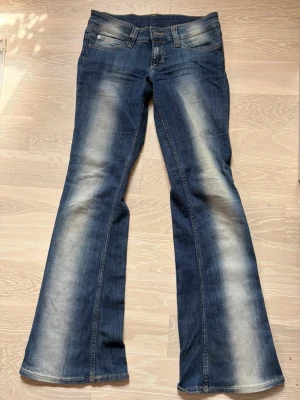 Blå bootcut jeans - Säljer dessa lågmidjade blåa bootcut  jeansen, med siktnings likande mönster. De är använda ett fåtal gånger och passar mig som är 165. 