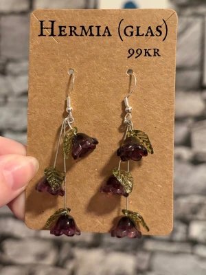 Hermia örhängen - Handgjort smycke med ett hänge i Sterling silver och finns i både guld och silver färg! Blommorna finns i 3 olika färger, mörk lila, ljus rosa och ljus blå