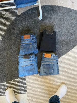 Fyra par jeans i olika blå nyanser - Säljer fyra par jeans i olika blå tvättar och ett par svarta jeans. Några av jeansen har slitningar och hål för en trendig look. Klassisk femficksmodell och raka ben. Perfekta för dig som gillar en avslappnad och cool stil.