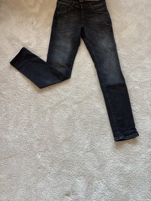 Svarta skinny jeans  - Säljer ett par svarta skinny jeans med snygga  tvättade detaljer. Klassisk femficksmodell med normalhög midja och smal passform. Jeansen har vita kontrastsömmar och är tillverkade i stretchigt denimtyg för extra komfort.