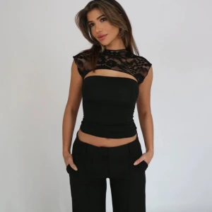 Svart spets topp med hög hals - Så snygg svart topp från Venderbys med croppad passform och transparent spets över axlar och rygg. Helt ny i skicket Köpt för 400 inkl frakt. 