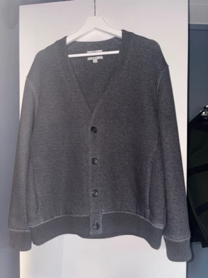 Mörkgrå kofta med knappar - Tjena! Säljer nu min mörkgrå kofta från COS med fyra knappar framtill. Koftan har en klassisk V-ringning och är tillverkad i mjukt bomullsmaterial. Perfekt för lager-på-lager och enkel att matcha med olika outfits. Passar även M eftersom den är relaxed. Det med kommer även en extra knapp som sitter inne i cardiganen. Om ni har frågor så hör av er. MVH Filip.