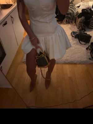 Vit kort klänning med volang - Säljer en söt vit kort klänning med volangkjol och figurnära överdel.  Perfekt för sommarens alla tillfällen speciellt studenten!!! Materialet känns lätt och bekvämt🫶🏻