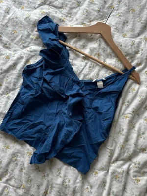 Blå blus - Så söt och somrig blå blus med volanger- och dragkedja framtill. 