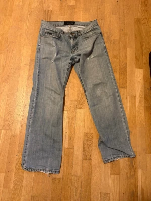 Ljusblå raka jeans från Blend - Säljer ett par ljusblå jeans från Blend med rak passform och klassisk femficksdesign sitter lite som flared/bootcut . Jeansen har slitningar framtill och snygga detaljer på bakfickorna. Tillverkade i denim med en avslappnad look, perfekta för en casual stil. Längd: 101cm