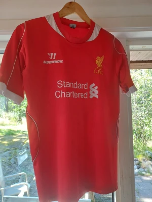 Liverpool fotbollströja Balotelli 45 - Röd Liverpool matchtröja från Warrior med vita detaljer, klubbmärke och sponsortryck på bröstet. På ryggen står det Balotelli och nummer 45. Perfekt för dig som älskar fotboll och vill visa ditt stöd för LFC. Storlek M. Kan har slitage på 45 men annars är den I perfekt skick.