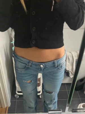 Ljusblå low waist ripped jeans - Säljer ett par ljusblå low waist jeans med slitningar på låren. Perfekta för en avslappnad och trendig look.