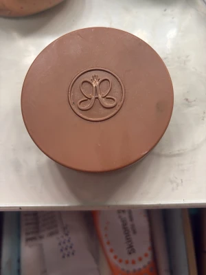 Bronzer från Anastasia Beverly Hills - Säljer en bronzer från Anastasia Beverly Hills i en rund, brun plastförpackning med det klassiska ABH-logotypen på locket. Perfekt för att ge ansiktet en solkysst look och definiera ansiktsdragen.