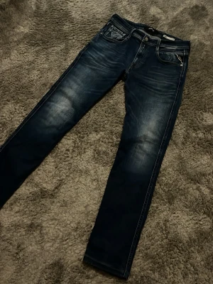 Mörkblå Replay jeans - Säljer ett par mörkblå jeans från Replay med tvättade detaljer på låren.  Raka ben och metallknapp. Perfekta för dig som gillar en avslappnad men trendig look. Sjukt snygga jeans men jag har tyvärr växt ut dem. 