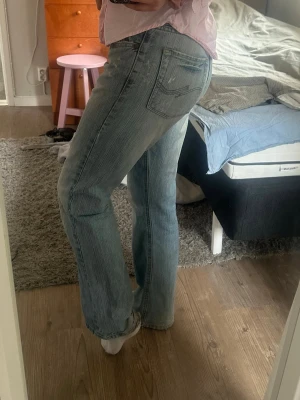 Ljusblå raka jeans - Säljer ett par ljusblå jeans med rak passform och klassisk femficksdesign. Jeansen har en något lösare siluett och subtila slitningar för en avslappnad look. Perfekta till vardagsstilen och passar till det mesta. Materialet är mjukt denim i bomull. Är lite trasiga längst ner. 