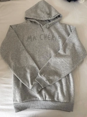 Grå hoodie med texten ”Ma Cherie” - Snygg grå hoodie med huva och texten 'MA CHERIE' broderad framtill. Storlek 158-164!!🩶🩶