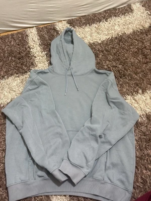 Ljusgrå hoodie från H&M - Snygg ljusgrå hoodie från H&M i relaxed fit. Klassisk modell med huva och dragsko, samt magficka framtill. Mjuk insida i fleeceliknande material som gör den extra skön att ha på sig. Perfekt för en avslappnad stil.