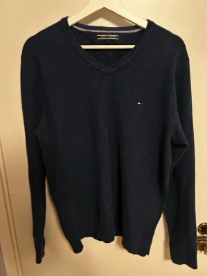 Tommy Hillfiger tröja  - Mörkblå stickad tröja från Tommy Hilfiger med V-ringning och logga på bröstet. Ändast använd fåtal gånger 9/10 skick skriv vid funderingar🙌