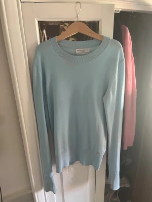 Ljusblå stickad tröja Holly & Whyte - Snygg ljusblå stickad tröja från Holly & Whyte med rund halsringning och långa ärmar. Tröjan har ribbade muddar vid hals, ärmslut och nederkant.   Skriv om fler bilder eller diskutera priset. 