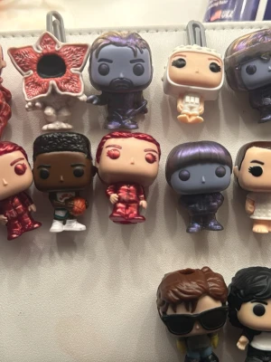 Nyckelringar med Stranger Things-tema - Säljer flera små nyckelringar med karaktärer från Stranger Things. Figurerna är färgglada och detaljerade, tillverkade i plast och har olika former och utseenden, inklusive monster och personer i olika outfits. Perfekt accessoar till cosplay eller maskerad.