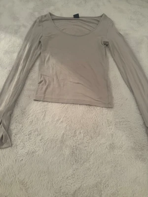 Beige långärmad topp - En enkel och stilren beige långärmad topp med rundad halsringning från Gina tricot. Ett litet hål vid höger arm (se bild 2) annars bra skick trots använd ganska mycket!