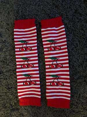 Randiga strumpor med körsbärsmotiv - Randiga lite tunna benvärmare. Storlek onesize. Längd 41 cm. Helt nya.