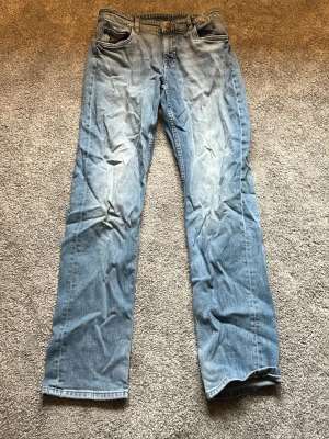 Ljusblå jeans kappahl  - Säljer ett par ljusblå jeans med raka ben och klassisk femficksmodell. Jeansen har en snygg tvätt med slitningar på låren och knäna för en avslappnad look. Tillverkade i bomull med dragkedjegylf och knapp i midjan.
