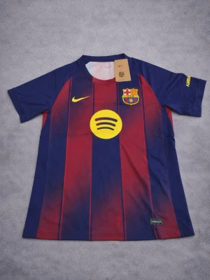FC Barcelona matchtröja Nike - Snygg FC Barcelona matchtröja från Nike med klassiska blå och röda vertikala ränder. Tröjan har klubbmärke, Nike-logga och Spotify-logga på bröstet samt UNHCR-tryck på ryggen. Tillverkad i lätt och ventilerande material, perfekt för fotboll eller träning.