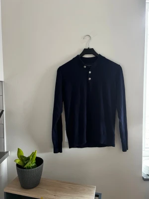  Mörkblå tröja med knappar från Grand Frank  - Stilren mörkblå långärmad tröja från Grand Frank med tre dekorativa knappar vid halsen. Passar dig  bra om du är mellan 150-160 cm!