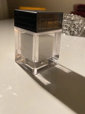 Glittrig highlighter  - Glittrigt vitt  highlighter pulver  transparent plastburk mönster. Pulvret skimrar i olika färger 