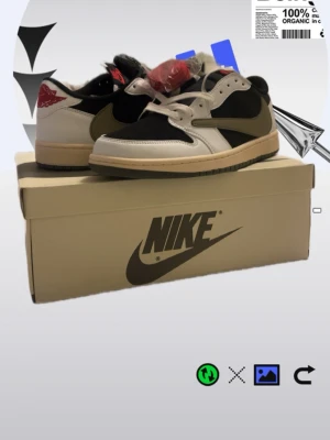 Nike Air Jordan 1 Low Travis Scott - Säljer ett par Nike Air Jordan 1 Low Travis Scott med svart och vit ovandel, olivgröna detaljer och omvänd swoosh. Skorna har röd logga på hälen och kommer med flera olika skosnören. Materialet är en mix av läder och textil. Priset går att diskuteras och de är äkta 
