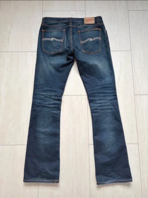 Nudie bootcut - Modell: Bootcut. Färg: blå/mörkblå. Storlek: W32/L32. Mått: W 41cm, Längd:106cm, benöppningen:22cm