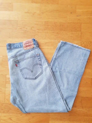 Levi's 505 - Klassiska ljusblå jeans från Levi's med rak passform och hög midja. Jeansen har fem fickor, Levi's ikoniska röda etikett på bakfickan och patch i läder bak i linningen. Tillverkade i slitstark bomullsdenim. Perfekta för en avslappnad och trendig look.