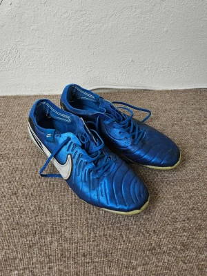 Nike Tiempo - Legend 10 elite AG - Säljer ett par Nike Tiempo Legend 10 AG i blå färg. Skorna är använda och har tydligt slitage, framför allt invändigt vid hälen (se bilder). Yttersulan och dobbarna är fortfarande i bra skick och funkar bra på konstgräs.  Perfekta som träningsskor eller för dig som vill ha ett billigare par att spela i.  Levereras snabbt!