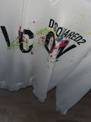 Vit hoodie Dsquared2 ICON färgstänk - Säljer en vit hoodie från Dsquared2 i storlek L, den är för liten för mig och har endast använts vid 5-6 tillfällen. Perfekt till sommaren!  Finns kvitto från KicksnStuff