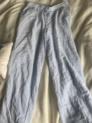 Randiga pyjamasbyxor i bomull - Ljusblå och vita pyjamasbyxor med tunna vertikala ränder. Byxorna har en avslappnad passform och resår i midjan för extra komfort. Tillverkade i mjuk bomull, perfekta för mysiga kvällar hemma.