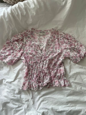 Blommig blus  - Blommig blus från Aware med puff ärm, v-ringning och knyte fram. Andvänd 1 gång