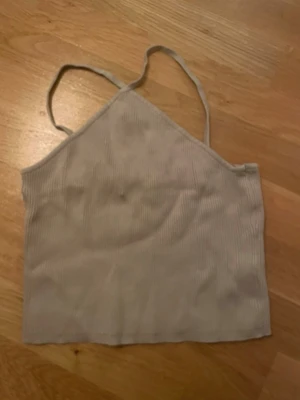 Beige ribbad linnetopp med smala band - Snygg beige linnetopp med smala axelband och ribbad struktur. Toppen har en enkel och stilren design med lätt croppad passform, perfekt till jeans eller kjol. Materialet känns mjukt och bekvämt mot huden.