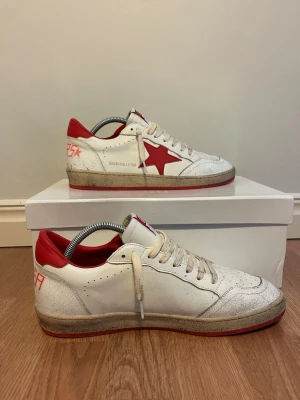 Golden Goose Ballstar - Golden Goose Ballstar sneakers i vitt läder med röd stjärna på sidan. Riktigt snygga dojor perfekt till sommaren. Skorna är något smutsiga men mycket av smutsen är del av designen. Enligt mig är detta den snyggaste Golden Goode modellen! Tveka inte på att höra av dig ifall du undrar något!✨
