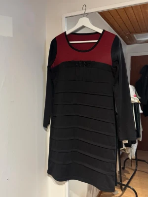 Svart och vinröd långärmad klänning - Snygg svart klänning med vinrött parti upptill och rund halsringning. Figurnära modell, helt ny!💕