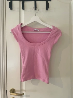 Rosa ribbad topp från Zara - Säljer en ljusrosa ribbad topp från Zara med rund halsringning och korta ärmar. Toppen är figurnära och har en enkel, stilren design som passar perfekt till jeans eller kjol. Aldrig använd, storlek s