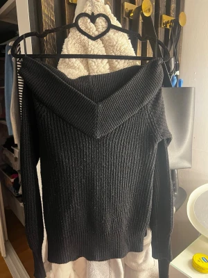 Svart off shoulder stickad tröja - Snygg svart stickad tröja från Gina Tricot i storlek XS. Tröjan har off shoulder-modell med bred krage och ribbstickad struktur. Lång ärm och mjukt material. 