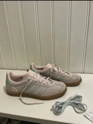 Adidas Gazelle ljusrosa sneakers - Snygga Adidas Gazelle sneakers i pastellrosa mocka med ljusgröna detaljer. Använda endast nån gång. Storlek 39 1/3. Bilder ifrån min Vinted.