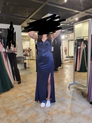 Balklänning - Mörkblå lång satinklänning med slits - Elegant mörkblå långklänning i satin med djup V-ringning, tunna axelband och hög slits på ena sidan. Figurnära passform som framhäver midjan och en stilren, glansig finish. Är 168cm lång. Nypris 2000kr säljer för 900kr, pris kan diskuteras