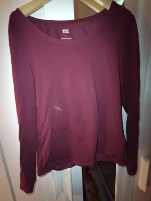 Mörkröd långärmad topp från 157 - Enkel och stilren mörkröd långärmad topp från 157. Toppen har rund halsringning och är tillverkad i mjuk bomull, perfekt för lager-på-lager eller som den är. Passar dig som gillar basic och bekväma plagg.