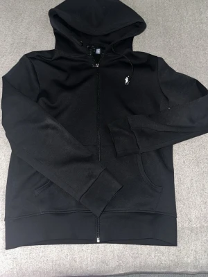 Svart hoodie från Polo Ralph Lauren - Svart Polo Ralph Lauren i nyskick, den är oanvänd. Klassisk och tidlös modell utan slitage. 