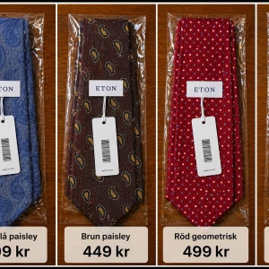 Fyra slipsar från Eton i olika mönster Paketpris  - Säljer fyra slipsar från Eton: en mörkblå med paisleymönster, en brun med paisleymönster, en röd med geometriskt mönster och en svart premiumslips med diskret mönster. Alla slipsar är i tyg och har klassisk form. Perfekta för att lyfta din outfit. Paketpris 1600kr. Nypris ca 1000–1500 kr/st – säljes till riktigt bra pris.