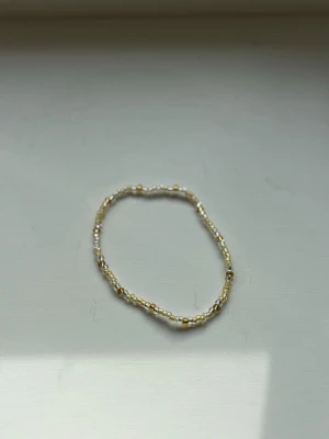 Gult pärarmband   - Snyggt armband med små pärlor i gul/guld. Armbandet är elastiskt och har en enkel, minimalistisk design. Ca 15cm. 