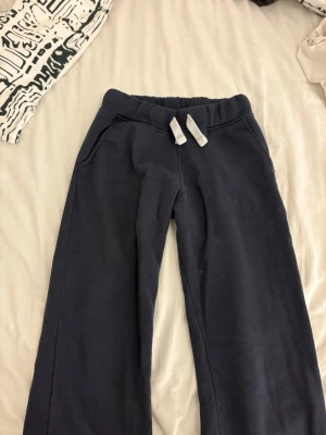 Mörkblå mjukisbyxor från Russemerch (tall) - Säljer ett par mörkblå mjukisbyxor med raka ben och vita snören i midjan. Byxorna har två sidofickor och är perfekta för chill dagar. Tillverkade i mjukt bomullsmaterial för extra komfort. Är i tall modellen 