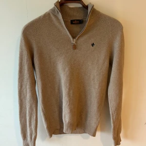Beige stickad tröja Morris XS - Snygg beige stickad tröja från Morris med halv dragkedja och liten broderad logga på bröstet. Tröjan har en lyxig style som jag personligen gillar mycket. Den är i storlek XS