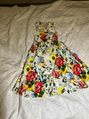 Lot 4 pcs loppis - Säljer en solgul omlottklänning med blommigt mönster och knytband på ärmarna. Klänningen har korta ärmar och är tillverkad i ett lätt material som passar perfekt för varma dagar.