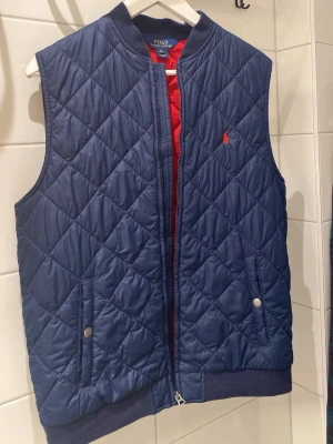 Blå dunväst från Polo Ralph Lauren - Schysst blå quiltad dunväst från Polo Ralph Lauren. Storlek: XL (18-20) men passar som (S) Skick: 8/10 (inga defekter förekommer). Mitt pris utgår från 425 men kan diskuteras! 